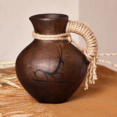 a brown vase sitting on top of a table next to a rope wrapped around it