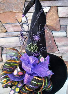 a witch hat with purple and green decorations on it's side next to a brick wall