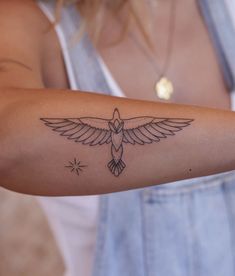 a woman's arm with a bird tattoo on it and stars in the background