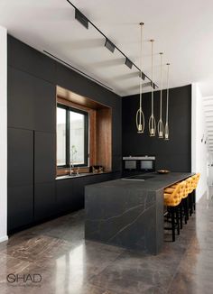 a kitchen with black walls and marble counter tops, yellow stools in front of the island