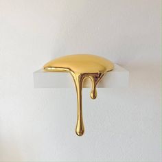 a gold dripping object on a white wall