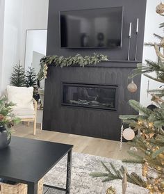 a living room decorated for christmas with a flat screen tv on the wall and fireplace