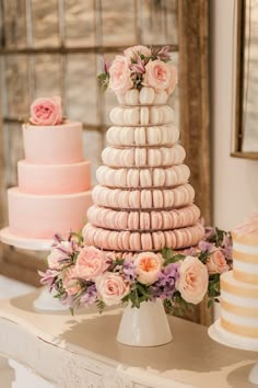 a wedding cake made out of macaroons and pink flowers on a white table