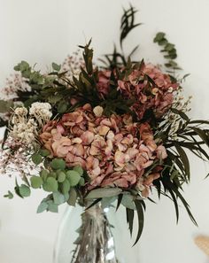 a vase filled with lots of flowers on top of a table