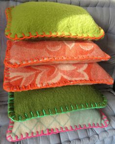 four pillows stacked on top of each other in different colors and patterns, one is orange, the other is green