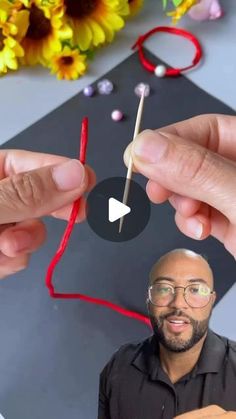 two hands are holding matches in front of a black board with red string on it