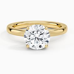 a yellow gold engagement ring with a round cut diamond in the center, on a white background