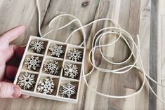 a person holding a box with snowflakes in it on a wooden floor next to a string