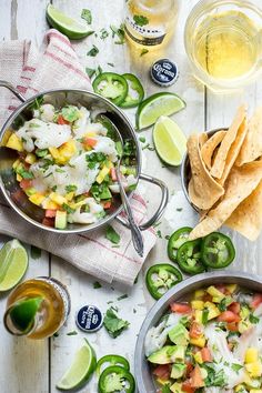 a table topped with bowls filled with food next to limes and tortillas