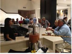 a group of people sitting at a counter in a room with food and drinks on it