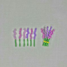 five small flowers are arranged in rows on a white tablecloth with green stems and purple beads