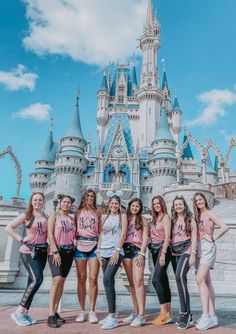 a group of girls standing in front of a castle with the words disney written on their shirts