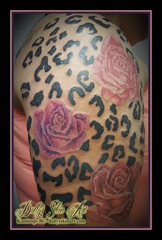 the back of a woman's shoulder with roses and leopard print tattoos on it