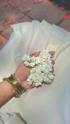 a woman's hand holding white flowers in her dress