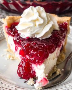 a slice of cheesecake with whipped cream and raspberry topping on a plate