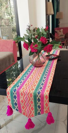 a vase filled with flowers sitting on top of a table covered in tassels