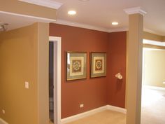 an empty room with two framed pictures on the wall and a doorway leading to another room