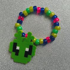 a green beaded bracelet with an alien face on it