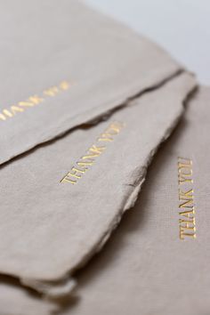 three pieces of paper with gold lettering on them