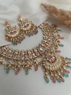 an elaborate necklace and earring set with pink, green and white stones on it