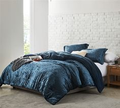 a bedroom with white brick walls and blue comforter