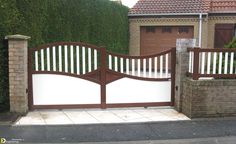 a gate that is next to a brick wall with a fence around it and a house in the background