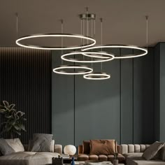 a living room with couches, chairs and lights hanging from the ceiling above them