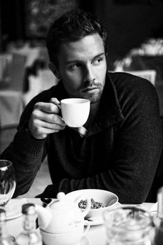 a man sitting at a table drinking from a cup