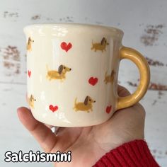 a hand holding a coffee cup with dogs on it and hearts all over the mug