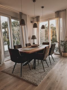 a dining room table surrounded by chairs in front of large windows