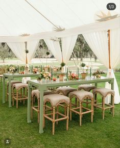 a table and chairs set up in the grass under a tent with white drapes