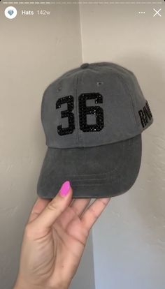 someone is holding up a hat with the number thirty six on it in front of a wall