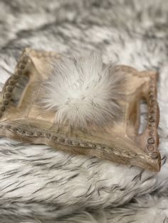 a decorative tray with feathers on top of it sitting on a fur covered bed sheet