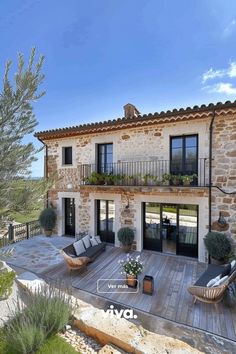 an outdoor patio with chairs and potted plants in front of a stone - built house