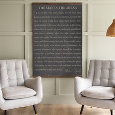 two chairs sitting next to each other in front of a wall with a framed poem on it