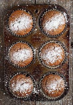 some cupcakes are sitting in a muffin tin with powdered sugar on top