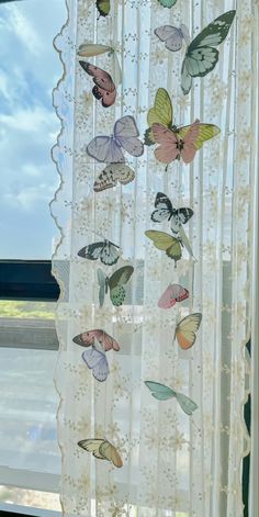 a curtain with butterflies hanging from it's side, in front of a window