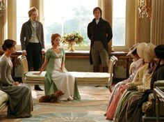 several people in period dress sitting and standing near a window