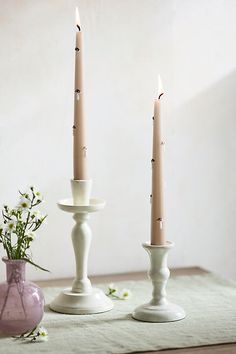 two white candles sitting on top of a table