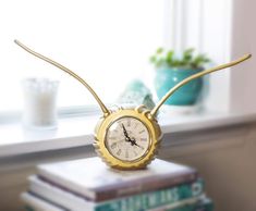 a clock sitting on top of a stack of books next to a window sill