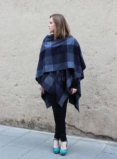 a woman standing on the sidewalk wearing a blue and black checkered ponchy