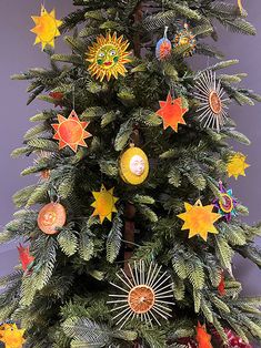 a small christmas tree with decorations on it's branches and star ornaments hanging from the top