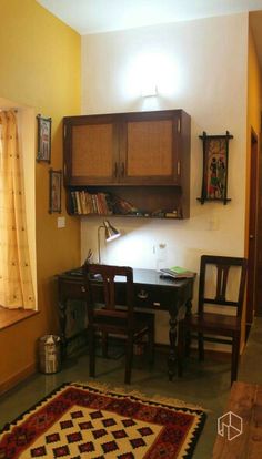 a room with a table, chairs and cupboards on the wall next to a rug