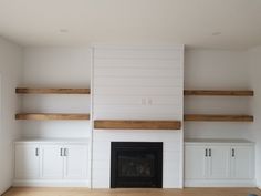 empty living room with fireplace and built - in shelving