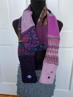 a mannequin with several different colored knitted scarves hanging from it's neck