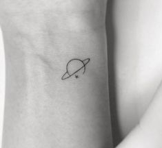 a small saturn tattoo on the left side of the arm, with a star at the center