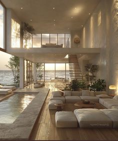 a living room filled with lots of furniture next to an ocean side house at sunset