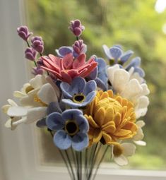 a vase filled with colorful flowers sitting on top of a window sill next to a window