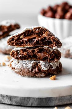 two chocolate crinkle cookies stacked on top of each other with powdered sugar