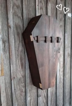 a wooden clock mounted to the side of a wall next to a wood paneled fence